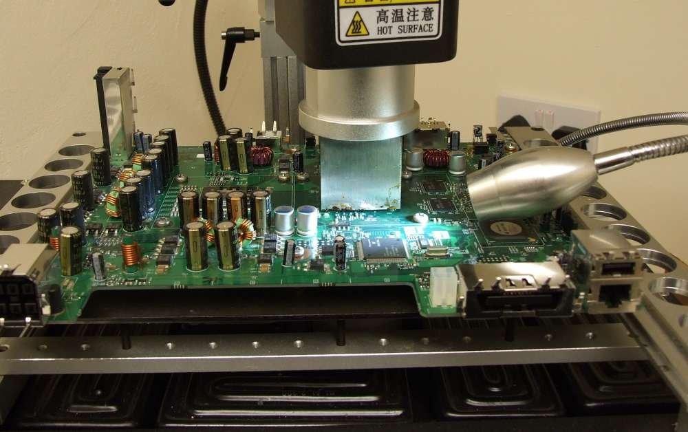 BGA rework workstation example | GlobalWellPCB Rework machine positioned above a populated electronic circuit-board assembly