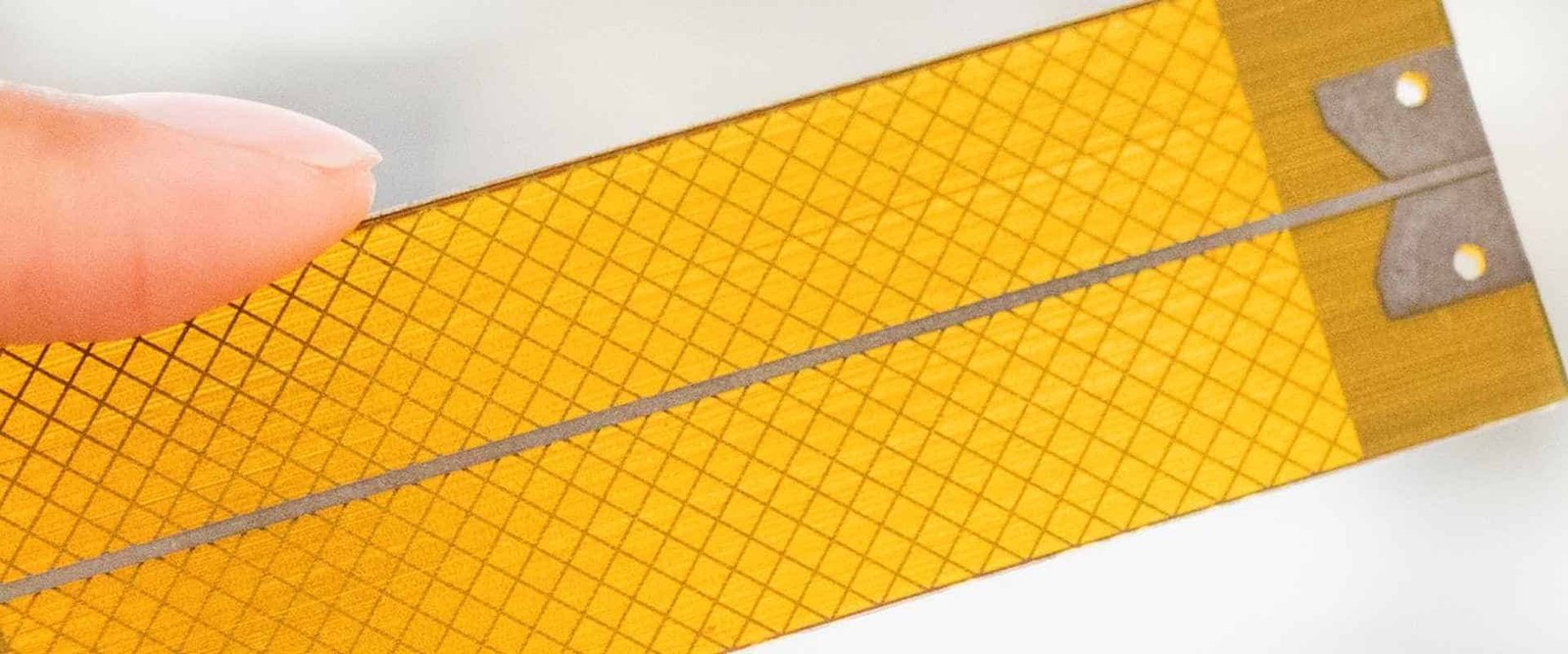 Flexible circuit copper mesh | GlobalWellPCB Close-up of a mesh pattern on an amber flexible circuit sheet