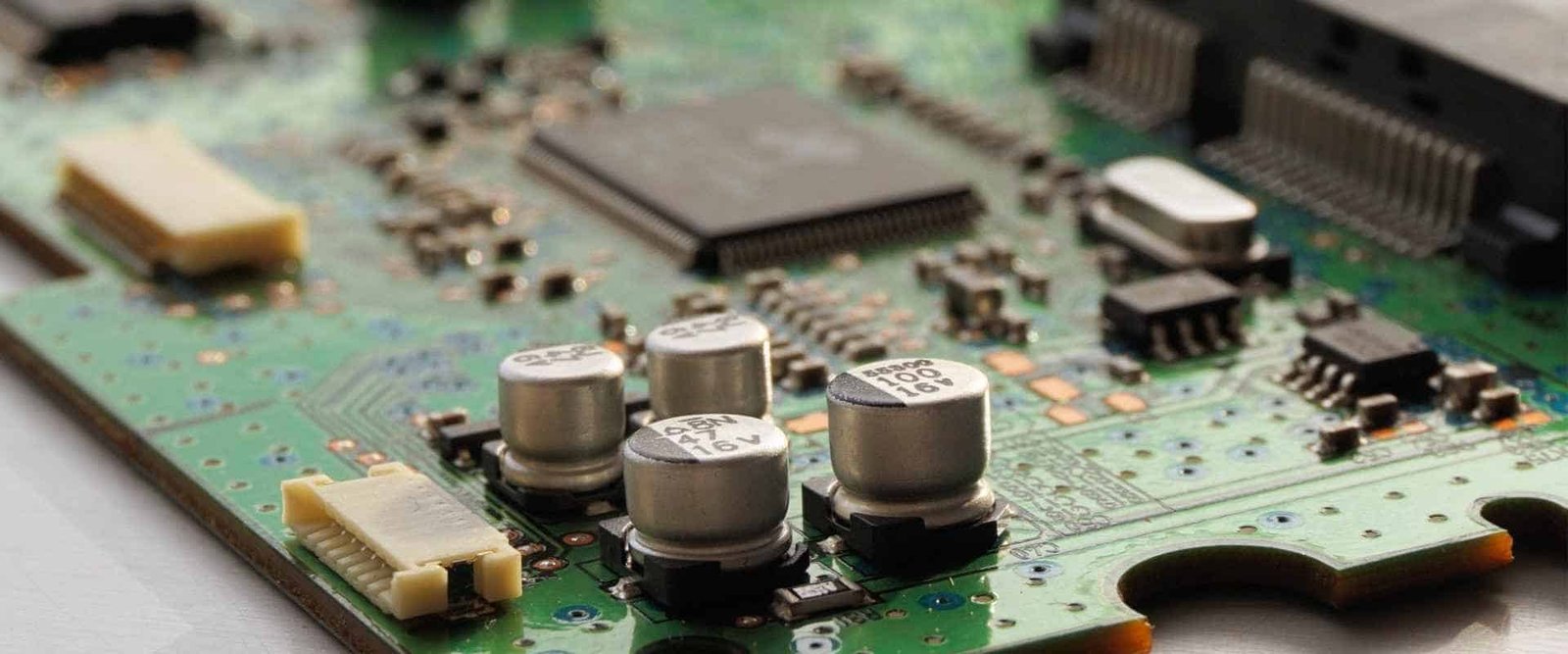 Populated circuit-board detail | GlobalWellPCB Populated green circuit board with integrated circuits, capacitors and connectors