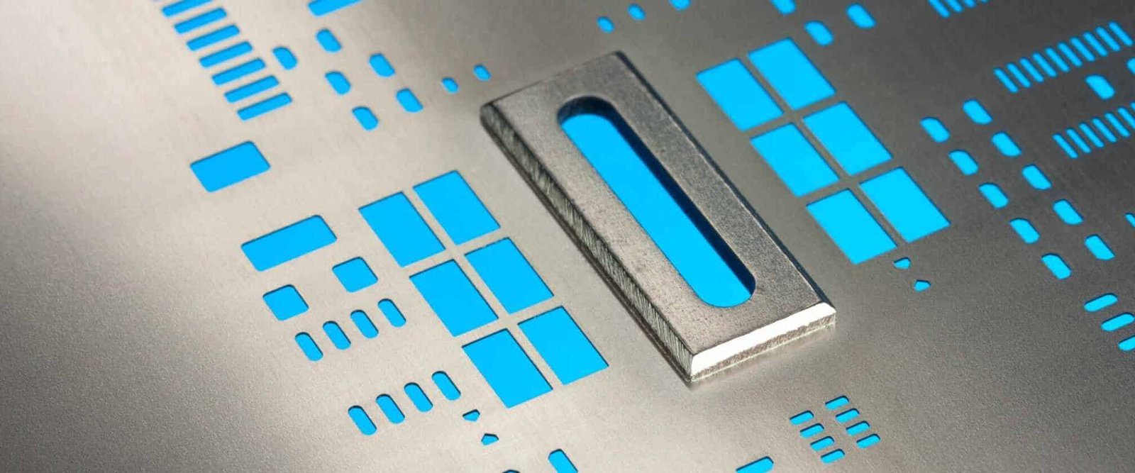 Close-up of a metal stencil with component apertures and a raised rectangular area